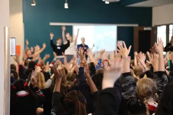 Students in a Drama for Schools programs raise their hands in a classroom